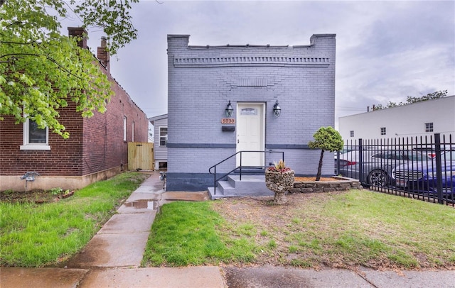 view of front facade featuring brick siding, fence, and a chimney