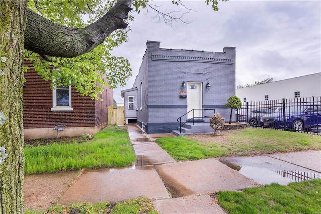 property entrance with brick siding, a lawn, and fence