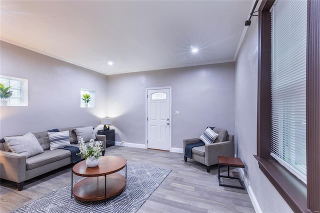 living area featuring recessed lighting, baseboards, ornamental molding, and light wood-type flooring