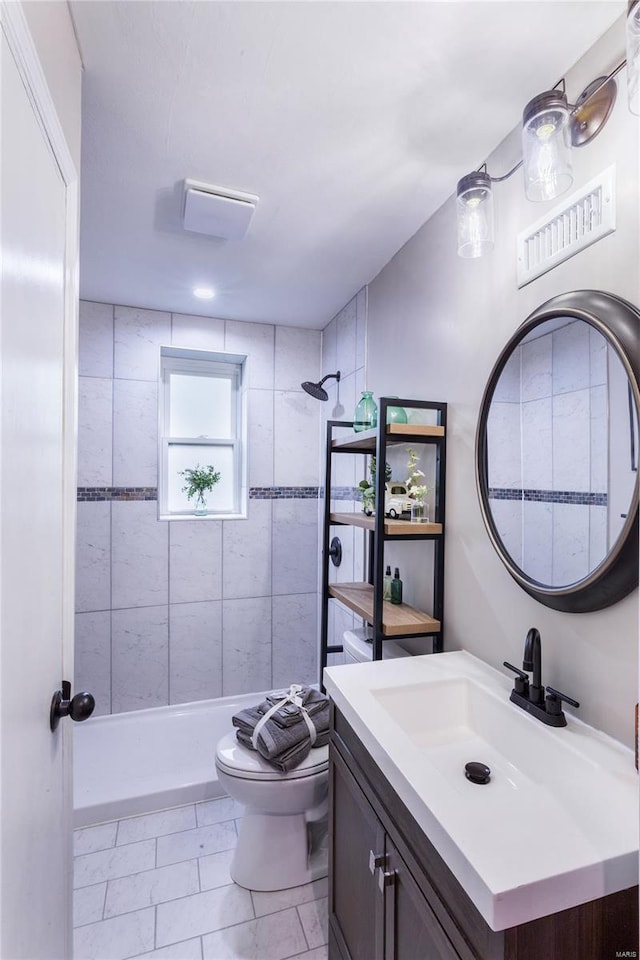 bathroom featuring visible vents, tile patterned flooring, vanity, toilet, and tiled shower