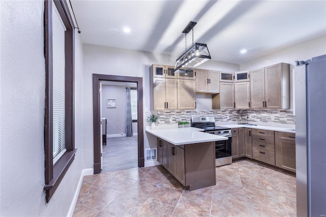 kitchen with a peninsula, decorative backsplash, appliances with stainless steel finishes, and light countertops