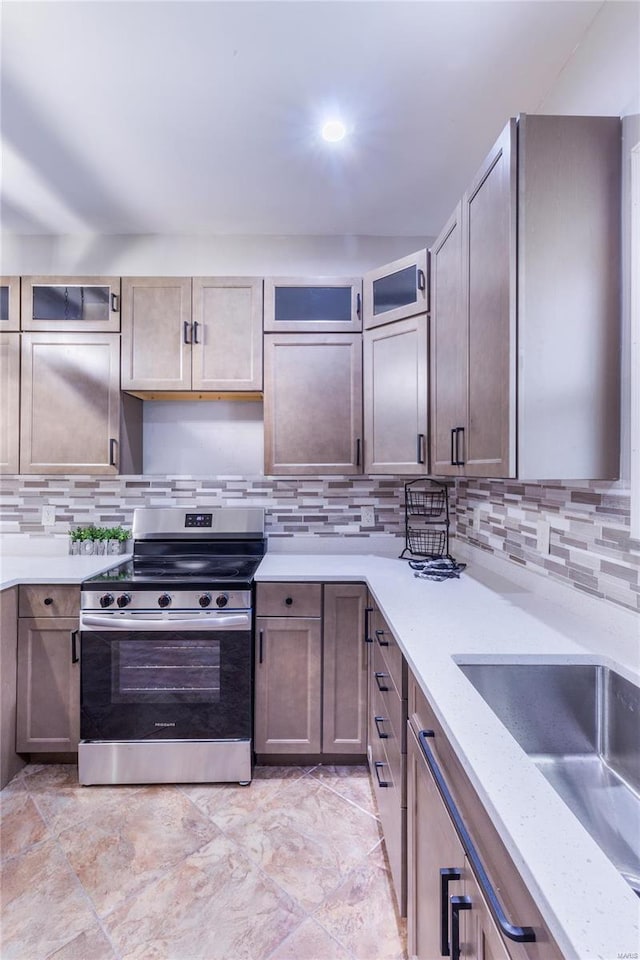 kitchen featuring light stone countertops, stainless steel electric stove, decorative backsplash, and glass insert cabinets