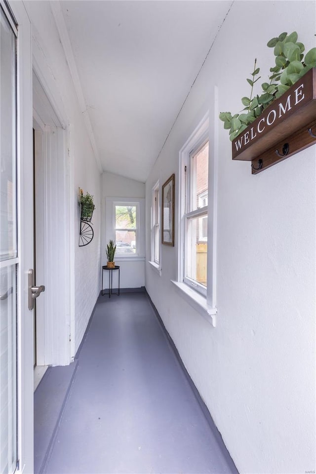 hallway featuring concrete flooring and lofted ceiling