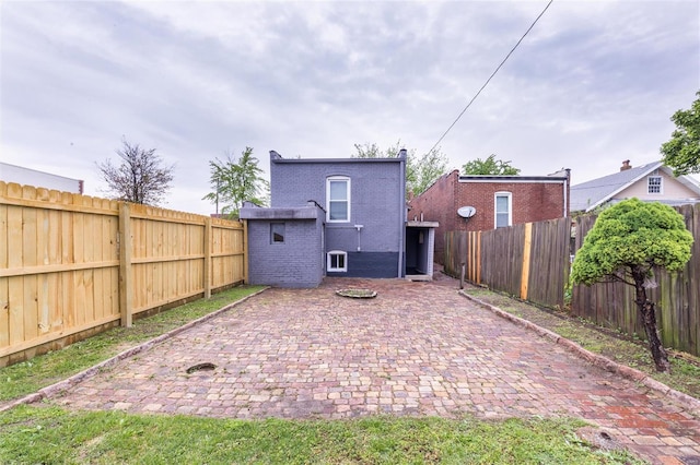 rear view of house with a fenced backyard, a patio area, and brick siding