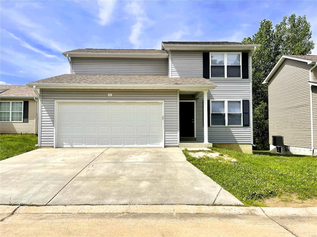 traditional home with a garage, central air condition unit, and driveway