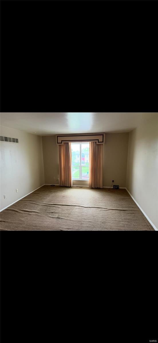 spare room with carpet floors, baseboards, and visible vents