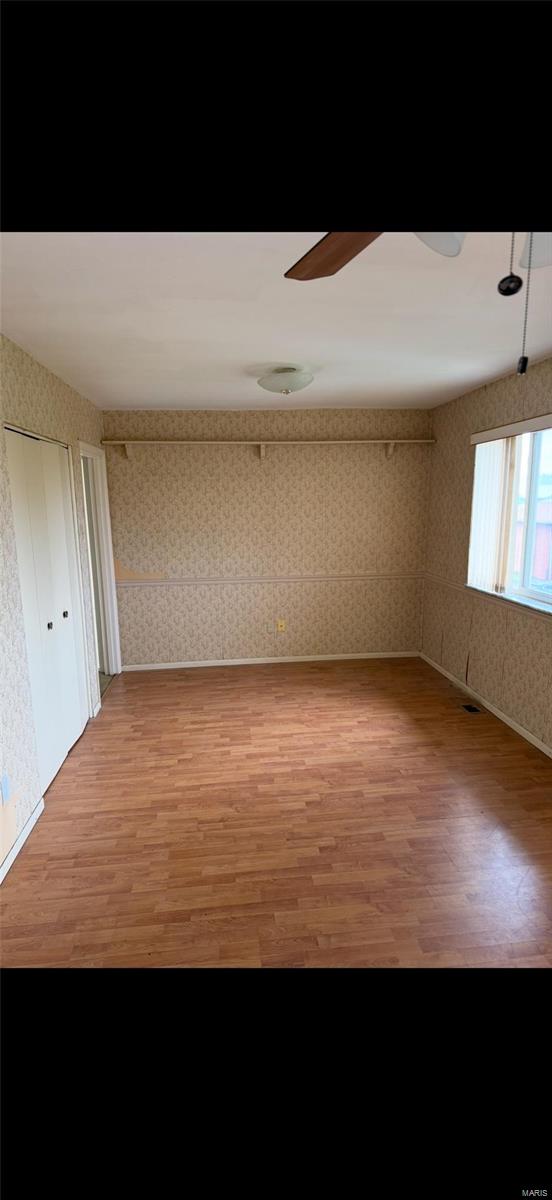 unfurnished room with baseboards, ceiling fan, light wood-style floors, and wallpapered walls