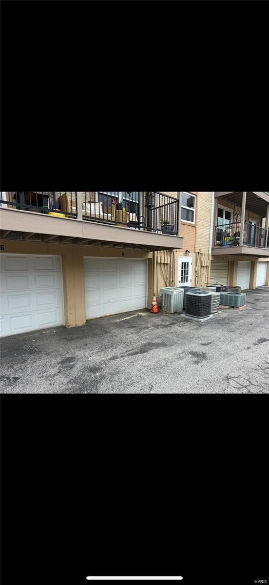 exterior space with a balcony, central air condition unit, and an attached garage