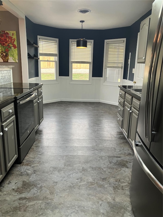 kitchen with a wainscoted wall, freestanding refrigerator, open shelves, electric range, and dark countertops