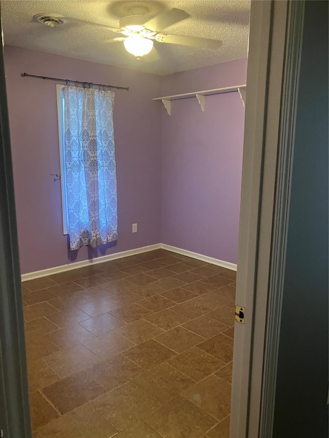 empty room featuring a ceiling fan, baseboards, visible vents, and a textured ceiling