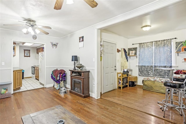 living area with light wood-type flooring, a ceiling fan, and ornamental molding