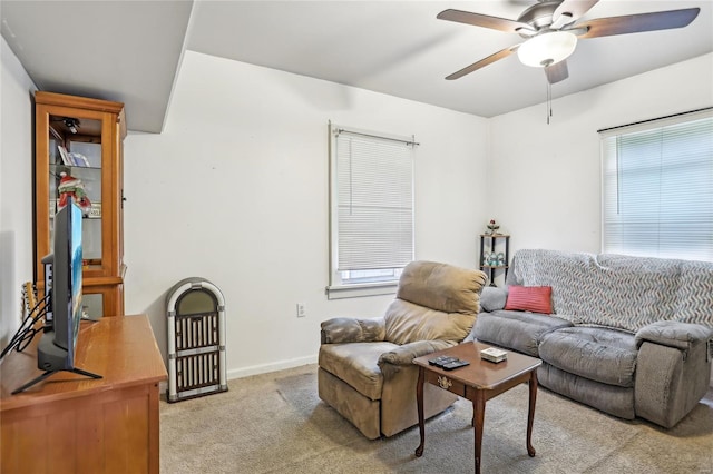 living room featuring baseboards, light carpet, and a ceiling fan