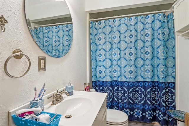 full bathroom with vanity, a textured wall, curtained shower, and toilet