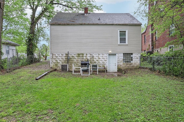 back of property featuring a fenced backyard, a chimney, and a yard