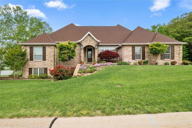 ranch-style home featuring roof with shingles, a front lawn, and brick siding