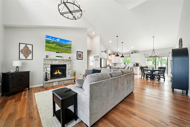 living area featuring a fireplace, high vaulted ceiling, a notable chandelier, recessed lighting, and hardwood / wood-style floors