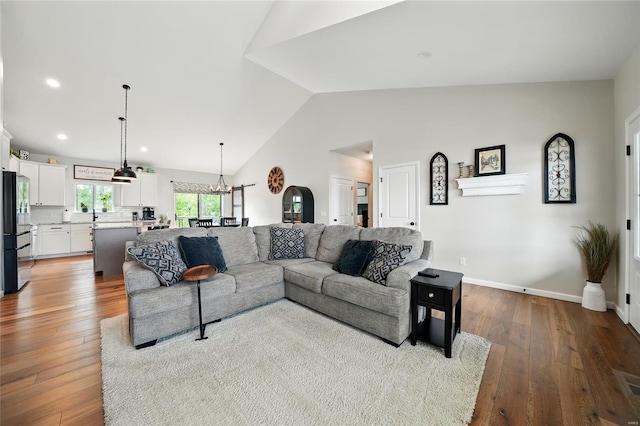 living area featuring a notable chandelier, hardwood / wood-style floors, recessed lighting, baseboards, and vaulted ceiling