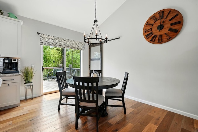 dining room featuring baseboards, an inviting chandelier, light wood-style flooring, and lofted ceiling
