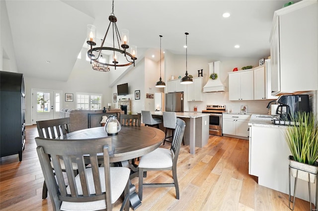 dining space featuring high vaulted ceiling, recessed lighting, light wood-style flooring, and a chandelier