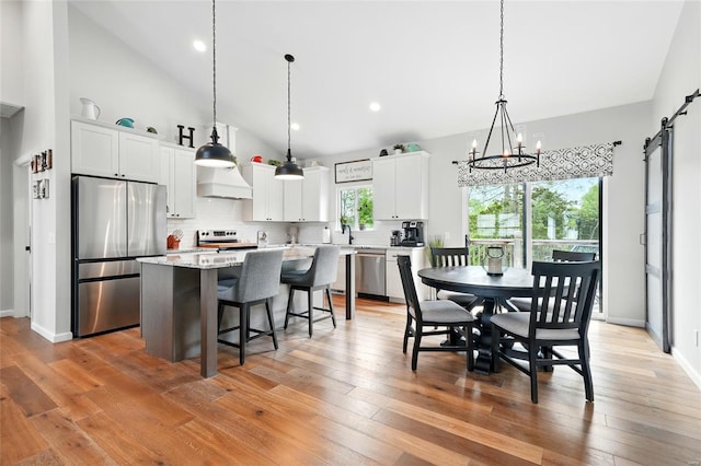 kitchen with a kitchen island, a breakfast bar area, a chandelier, appliances with stainless steel finishes, and backsplash