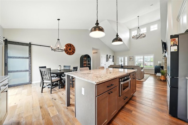 kitchen featuring an inviting chandelier, open floor plan, light wood-style flooring, and stainless steel appliances