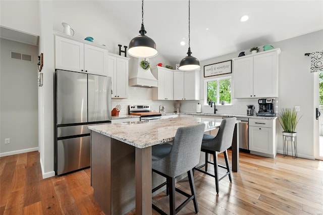 kitchen featuring custom range hood, decorative backsplash, visible vents, and stainless steel appliances