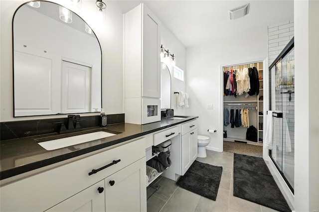 bathroom featuring a sink, double vanity, tile patterned floors, visible vents, and a stall shower