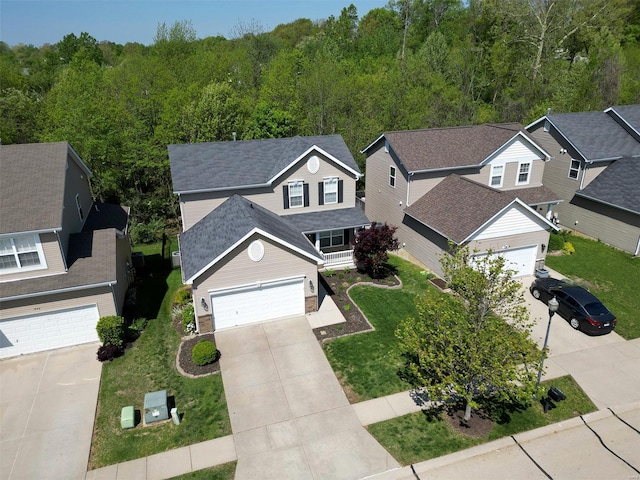 view of front of home with a forest view, a shingled roof, driveway, and a front yard