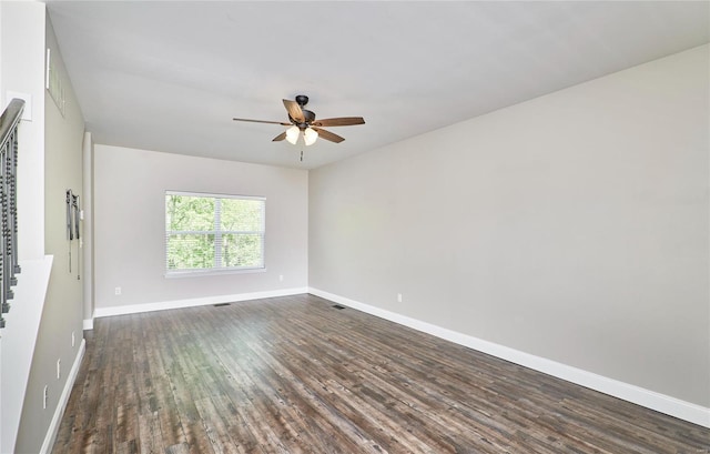 empty room with baseboards, a ceiling fan, dark wood-style floors, and visible vents