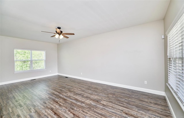 empty room featuring baseboards, a ceiling fan, dark wood-style floors, and visible vents