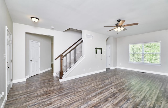 unfurnished living room featuring visible vents, dark wood-style flooring, baseboards, stairway, and a ceiling fan