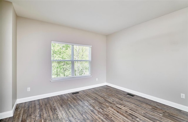 unfurnished room featuring baseboards, visible vents, and dark wood-type flooring