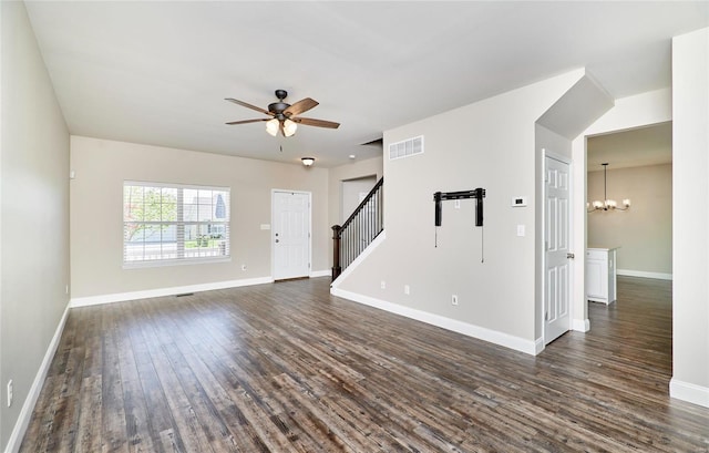 unfurnished living room featuring visible vents, dark wood-style flooring, stairs, baseboards, and ceiling fan with notable chandelier