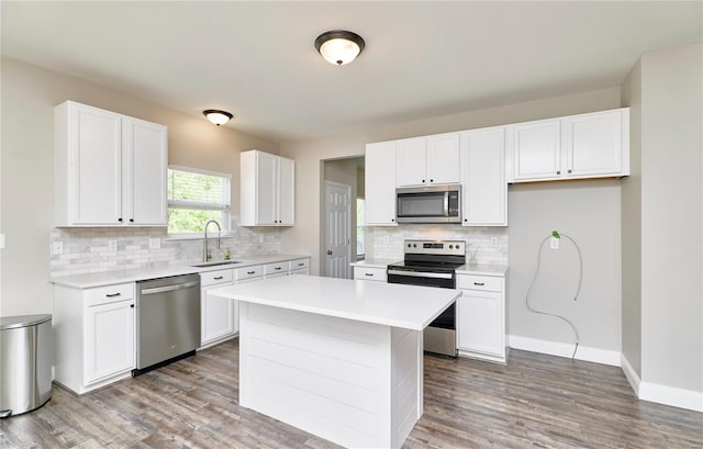 kitchen with decorative backsplash, wood finished floors, light countertops, a sink, and appliances with stainless steel finishes
