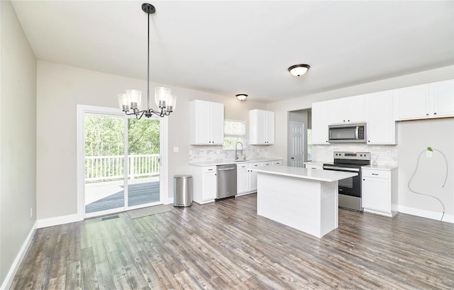kitchen with wood finished floors, light countertops, tasteful backsplash, appliances with stainless steel finishes, and a notable chandelier