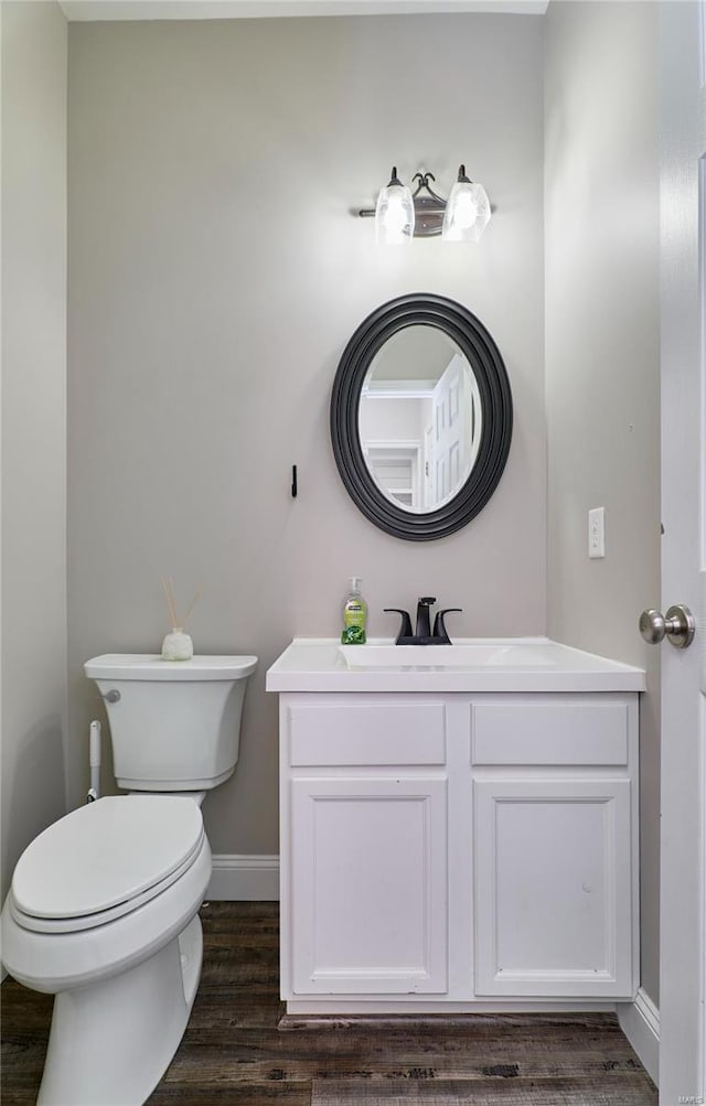 bathroom with vanity, baseboards, wood finished floors, and toilet