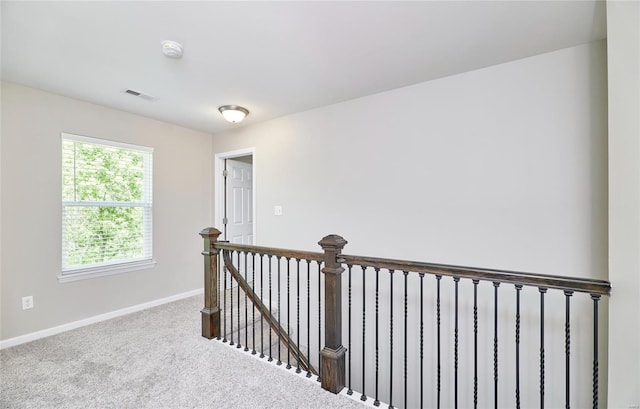 hallway with visible vents, carpet flooring, baseboards, and an upstairs landing