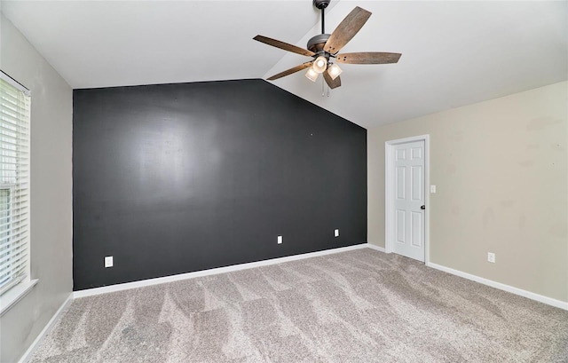 carpeted spare room with ceiling fan, baseboards, and lofted ceiling