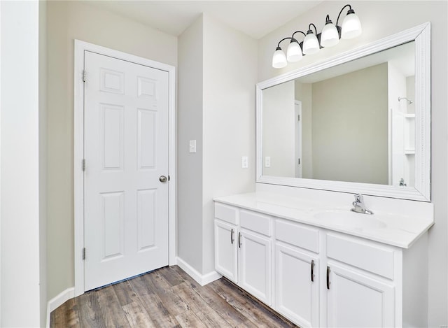 bathroom with baseboards, wood finished floors, and vanity