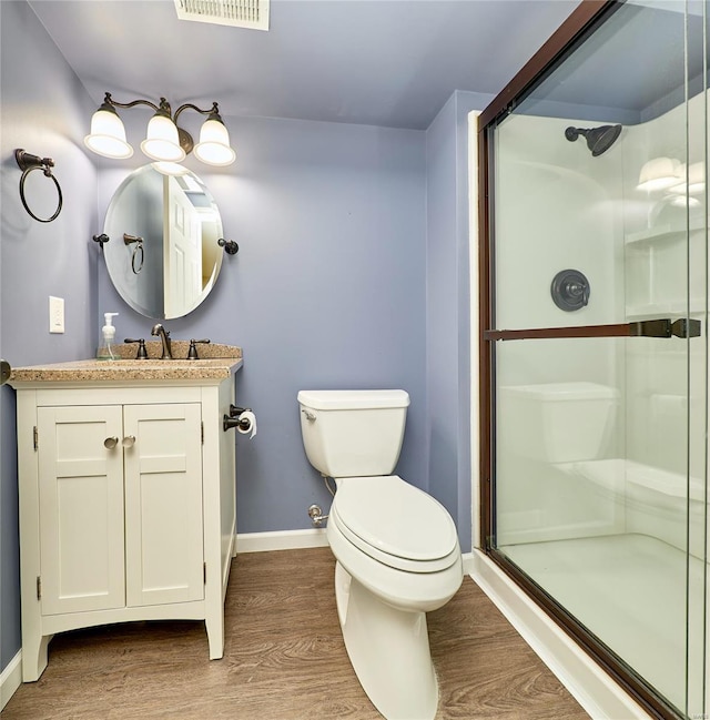 full bath with baseboards, a shower stall, toilet, and wood finished floors