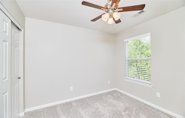 spare room with a ceiling fan, baseboards, visible vents, and carpet