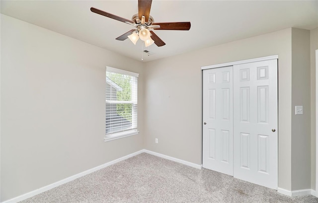 unfurnished bedroom featuring a closet, carpet flooring, baseboards, and ceiling fan