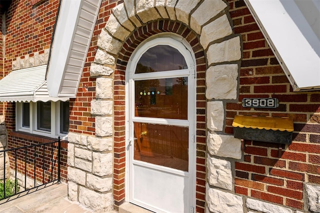 entrance to property featuring brick siding and stone siding