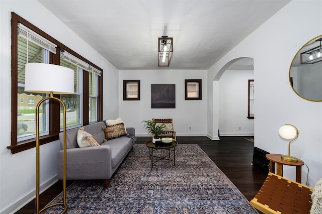 living room with baseboards, arched walkways, and wood finished floors