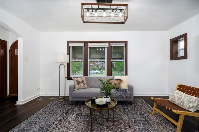 sitting room featuring arched walkways, baseboards, dark wood finished floors, and a notable chandelier