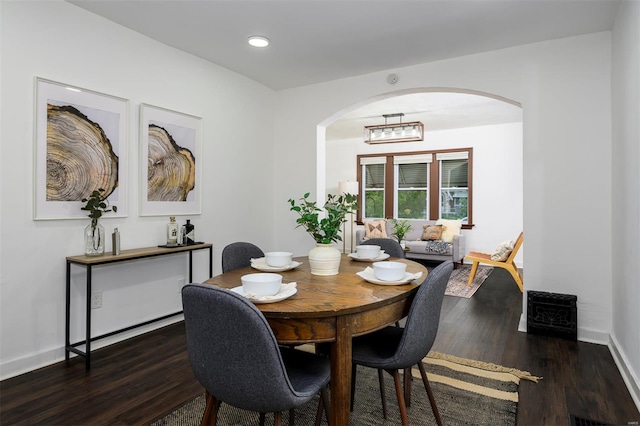dining room featuring baseboards, arched walkways, wood finished floors, and recessed lighting