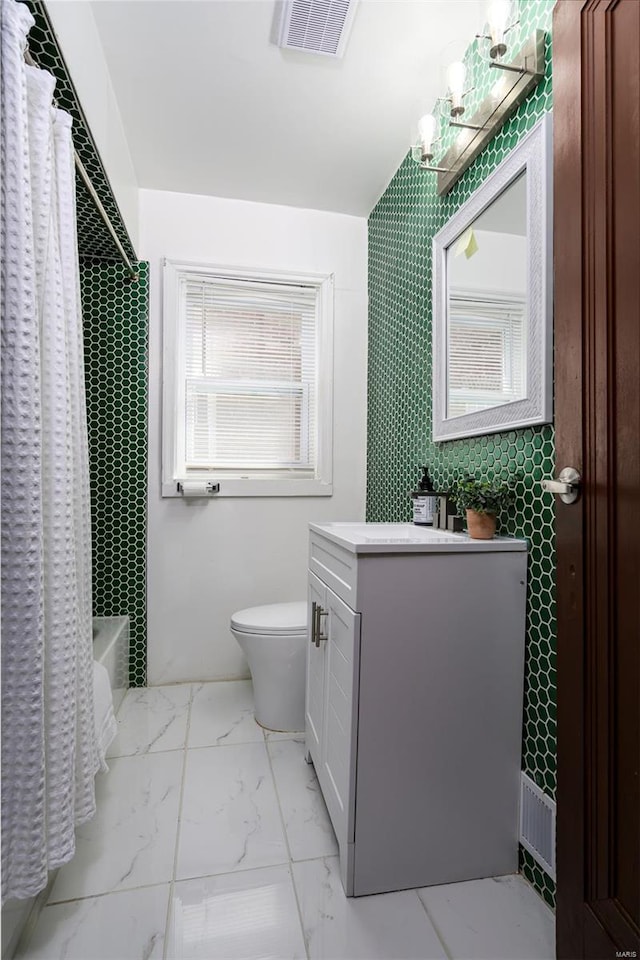 full bath with vanity, toilet, shower / bath combo with shower curtain, marble finish floor, and visible vents