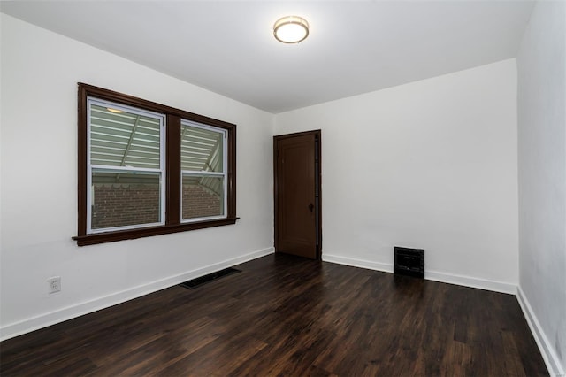 empty room featuring baseboards, wood finished floors, and visible vents