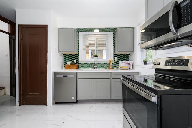 kitchen featuring marble finish floor, light countertops, gray cabinets, a sink, and appliances with stainless steel finishes