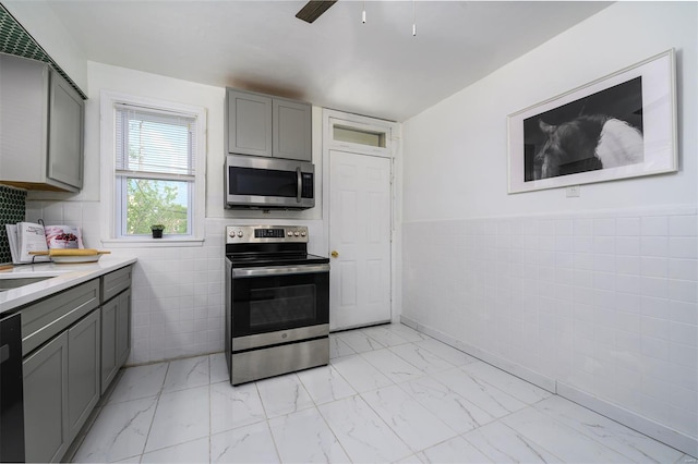 kitchen with tile walls, gray cabinetry, and stainless steel appliances